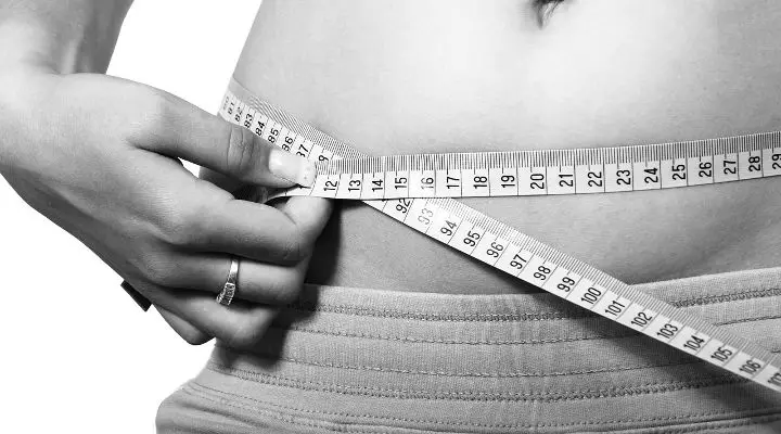 Image of person measuring their waist. If you are looking for a paleo weight loss plan or paleo diet weight loss advice, this article will get you on your way