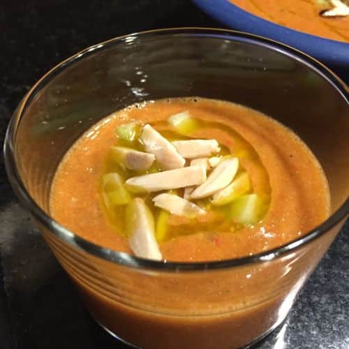 classic paleo gazpacho soup recipe served in a clear glass with almond and olive oil garnishe