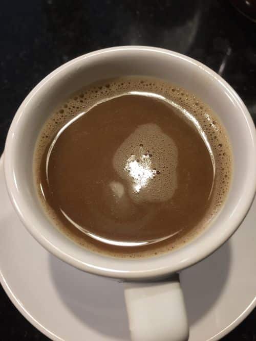 A photo from top of dark brew of coffee blocks in a mug. Coffee blocks are a way to start drinking butter in the morning with packets containing a bullet coffee coconut oil blend. If you are looking for coffee with butter in it, especially if you are often on the road, Coffee Blocks are a great option.